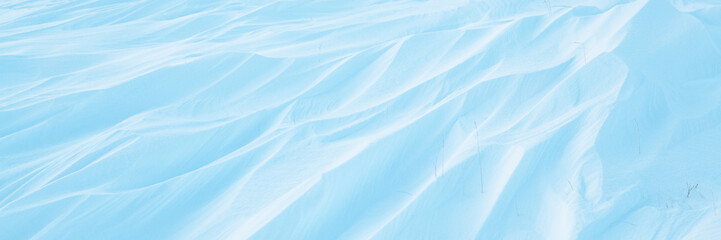 Snow texture. Wind sculpted patterns on snow surface. Wind in the tundra and in the mountains on the surface of the snow sculpts patterns and ridges (sastrugi). Arctic, Polar region. Winter background