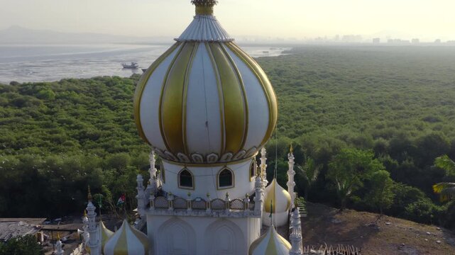 Top down drone shot pushing towards onion dome with upward tilt on coastal mausoleum