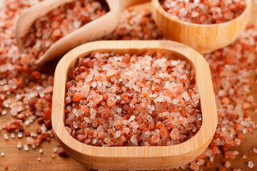 Himalayan salt crystals in a wooden bowl on a rustic wooden table