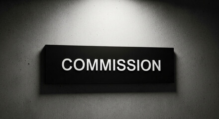 Rectangular black plate with white "COMMISSION" text mounted on textured gray concrete wall under spotlight, representing delegation, task, request