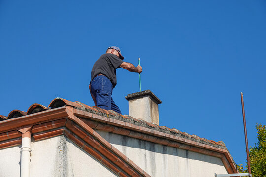 A person works on a chimney atop a house
