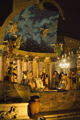 Roma , Italia , San Peter Square 12-18-2025. Nighttime Nativity Scene With Starry Arch, Festive Market Square, And Large Christmas Tree