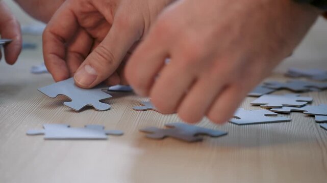 Assembling puzzle piece with hand in teamwork and collaboration as group connect jigsaw piece on wooden table with finger guidance focusing on interlock process and cooperative problem solving