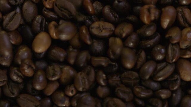 Falling coffee beans in slow motion. Smoke emanates from fresh coffee beans 