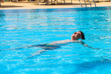 Adult Man Floating on His Back in the Pool Egyptian Hotel, Enjoying a Relaxing Day Under the Sun in a Tropical Paradise.