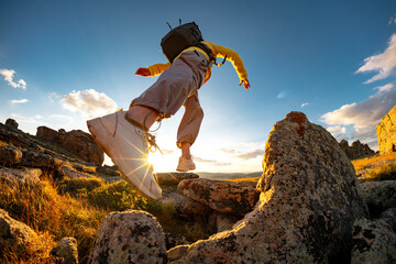 Close up photo of walking hiker legs moving at rocky terrain against sunset sky