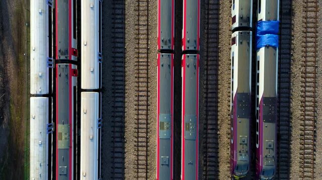 Aerial drone footage of large train yard depot, carriages and railway tracks, sunny afternoon in Ely, United Kingdom. 