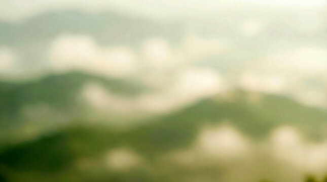 Soft focus view of misty green mountain ranges shrouded in clouds during sunrise - Powered by Adobe