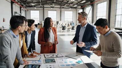 Diverse business team collaborates on a project at a modern office table with charts and tablets - Powered by Adobe