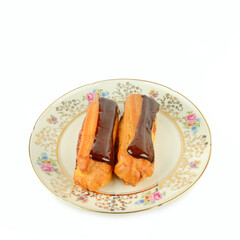 Two chocolate eclairs served on a vintage floral porcelain plate.
