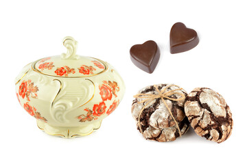 Vintage porcelain sugar bowl with heart-shaped chocolates and brownies isolated on white.
