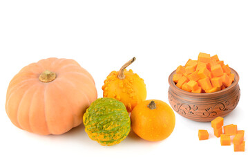 Whole pumpkins and a ceramic bowl with orange pumpkin cubes isolated on white.