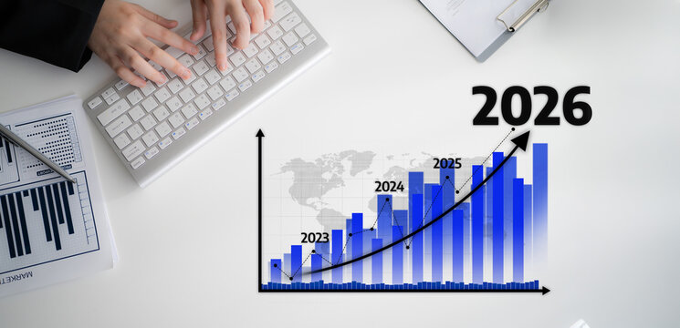 A close-up view of a keyboard and a business growth projection chart for 2026, illustrating financial analysis and data visualization in a modern office setting. Tessel - Powered by Adobe