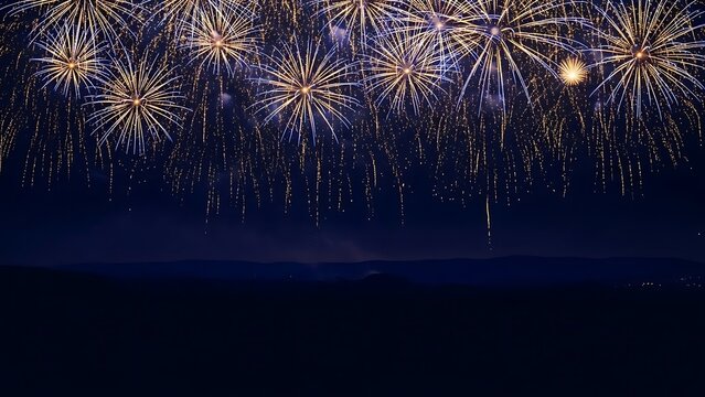 Spectacular golden fireworks display exploding in the dark night sky over distant horizon - Powered by Adobe