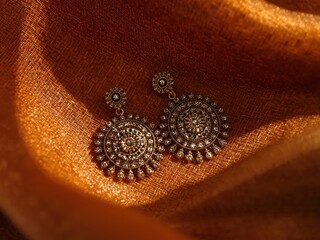 Elegant traditional earrings on orange fabric