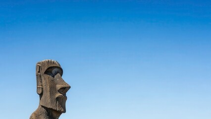 A large stone statue stands against a clear blue sky on a sunny day outdoors.