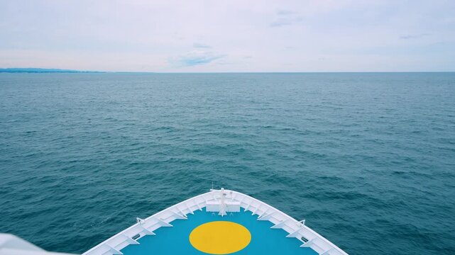 A luxury cruise ship sails from Yokohama to Miyako Port in Japan. View from the upper deck shows the bow heading into the deep blue Pacific Ocean.