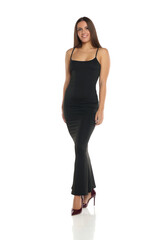 Fototapeta premium Studio shot of a smiling woman with dark hair wearing a long black dress and high heels, standing in a relaxed pose, full body, on a white background
