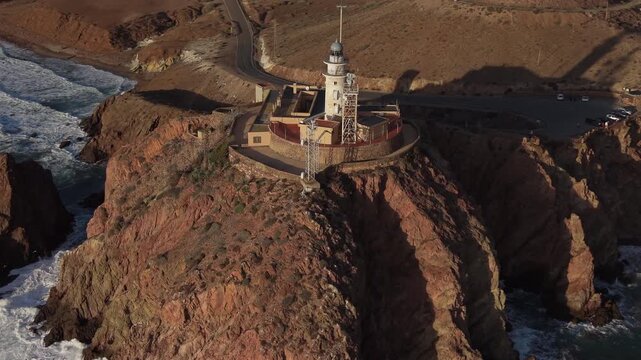 Aerial view of the Cabo de Gata lighthouse and cliffs on the Almeria coast during a golden sunset