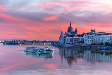 Fototapeta premium View of Budapest Parliament under sunset sky and cruise ship on the Danube, Hungary