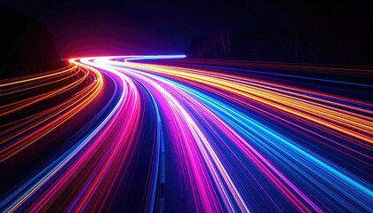 Long exposure captures blurred vehicle trails as streams of light on a winding roadway at night