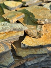 Natural stone slabs stacked in sunlight, perfect for use as a rustic textured background