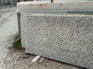Granite slabs stacked outdoors on construction site, showcasing natural stone texture background