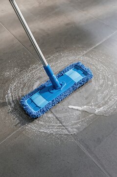 A precise cleaning moment is caught as a microfiber mop clears dirt from gray tiles