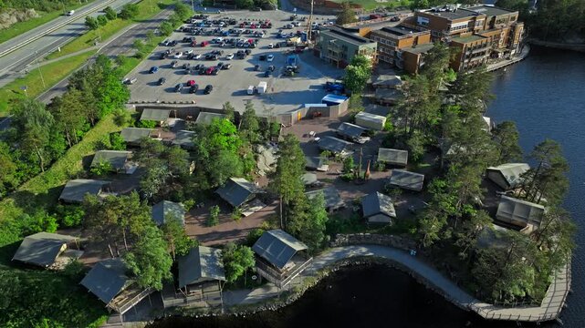 The canvas tent cabins in the forest, animal enclosures, parking area, and nearby hotel buildings identify this as the SafariCamp accommodation area next to Dyreparken.
