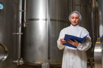 Expertise female wine maker working and inspecting wine in fermenting room 