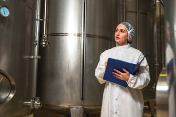 Expertise female wine maker working and inspecting wine in fermenting room 