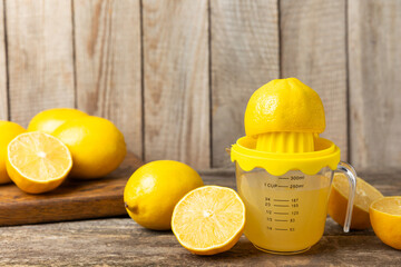 Lemon juice. Fresh lemon juice in a bowl. Ripe citrus, mint, fruit, and a juicer on the table. Vitamin C. Lemon water. Ingredient for baking or salad dressing. Space for text. Copy space.