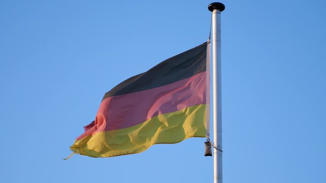 German flag blowing in the wind, blue sky in the background, national pride