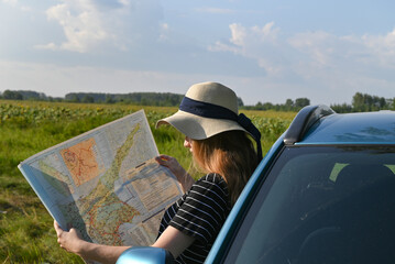 Rear view shot of couple driving on country road. Woman holding map and showing the route map to her boyfriend driving the car. Couple on a road trip. © Svetlana Verbitskaya