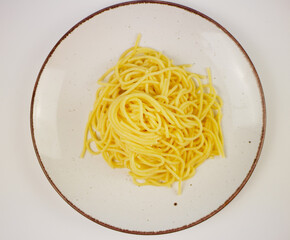 White plate full of cooked spaghetti with a small piece of butter in the middle, top view on neutral background, minimal hot pasta dish for menu design