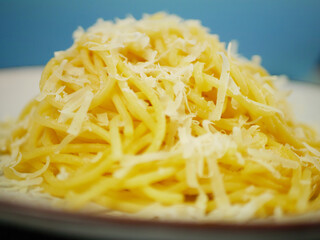 Side closeup of hot spaghetti piled high and topped with grated parmesan cheese on a plate, appetizing cheesy pasta portion for Italian comfort food concepts. Pro Photo
