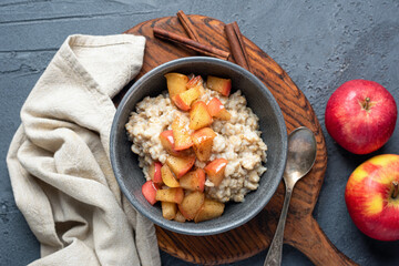 Cooked oatmeal porridge with caramelized apples, cinnamon. Autumn, winter comfort food, healthy dessert for breakfast. Top view
