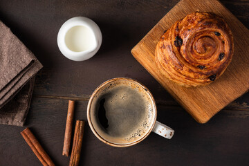 Cup of black coffee and sweet cinnamon raisin swirl bun