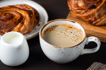 Cup of black coffee and sweet cinnamon raisin swirl bun