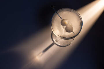 Gibson martini on a reflective white surface with high contrast lighting and contrasting tones.