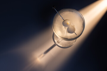 Gibson martini on a reflective white surface with high contrast lighting and contrasting tones.