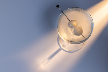 Gibson martini on a reflective white surface with high contrast lighting and contrasting tones.