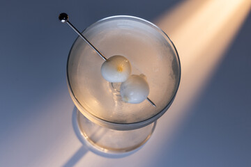 Gibson martini on a reflective white surface with high contrast lighting and contrasting tones.