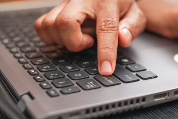 Close up of a Hand Pressing the Enter Key on a Laptop Keyboard Indoors
