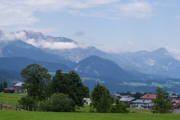 Scenic mountain countryside with open meadows, forested slopes and small rural homes. Calm natural environment, fresh air, travel destination and outdoor lifestyle concept.