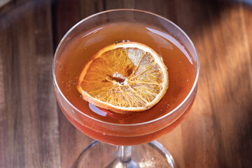 whiskey cocktail or manhattan served up garnished with a dehydrated orange slice.