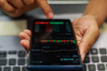 Fingers Pointing At Stock Market Data On Smartphone Screen Displaying Candlestick Charts And Graphs