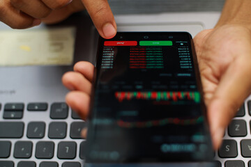 Fingers Pointing At Stock Market Data On Smartphone Screen Showing Red And Green Bars And Graphs