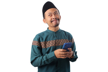 Smiling Asian Muslim man in green traditional outfit joyfully browsing or texting on his phone, symbolizing online shopping or connection during Ramadan. Isolated on white background
