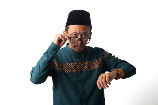 Serious Asian Muslim man checking the time on his wristwatch while waiting for iftar or suhoor before imsak during Ramadan fasting. Isolated on a white background, time management and fasting concept